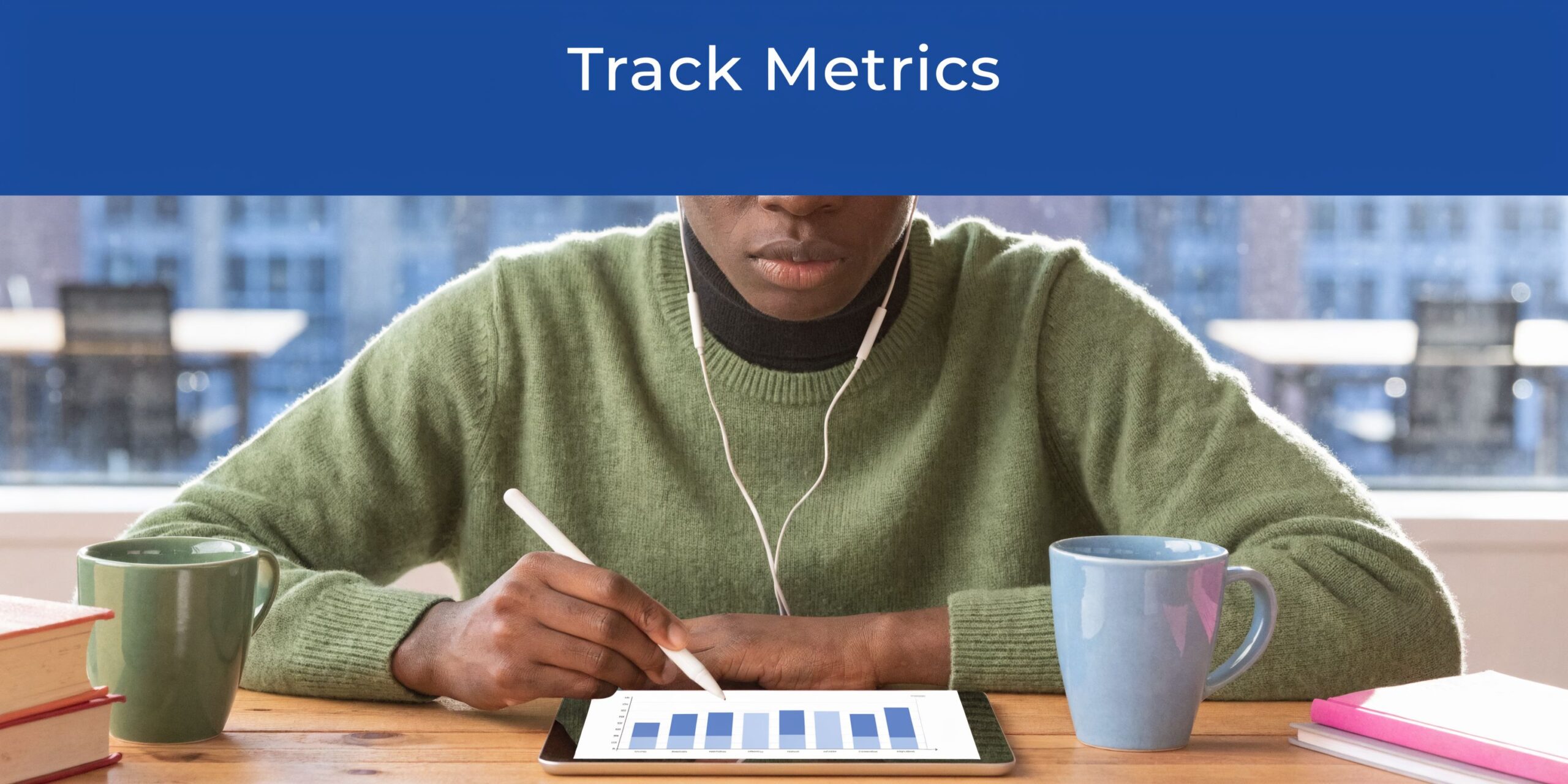 A person wearing a green sweater using a stylus on a tablet showing charts at a desk.