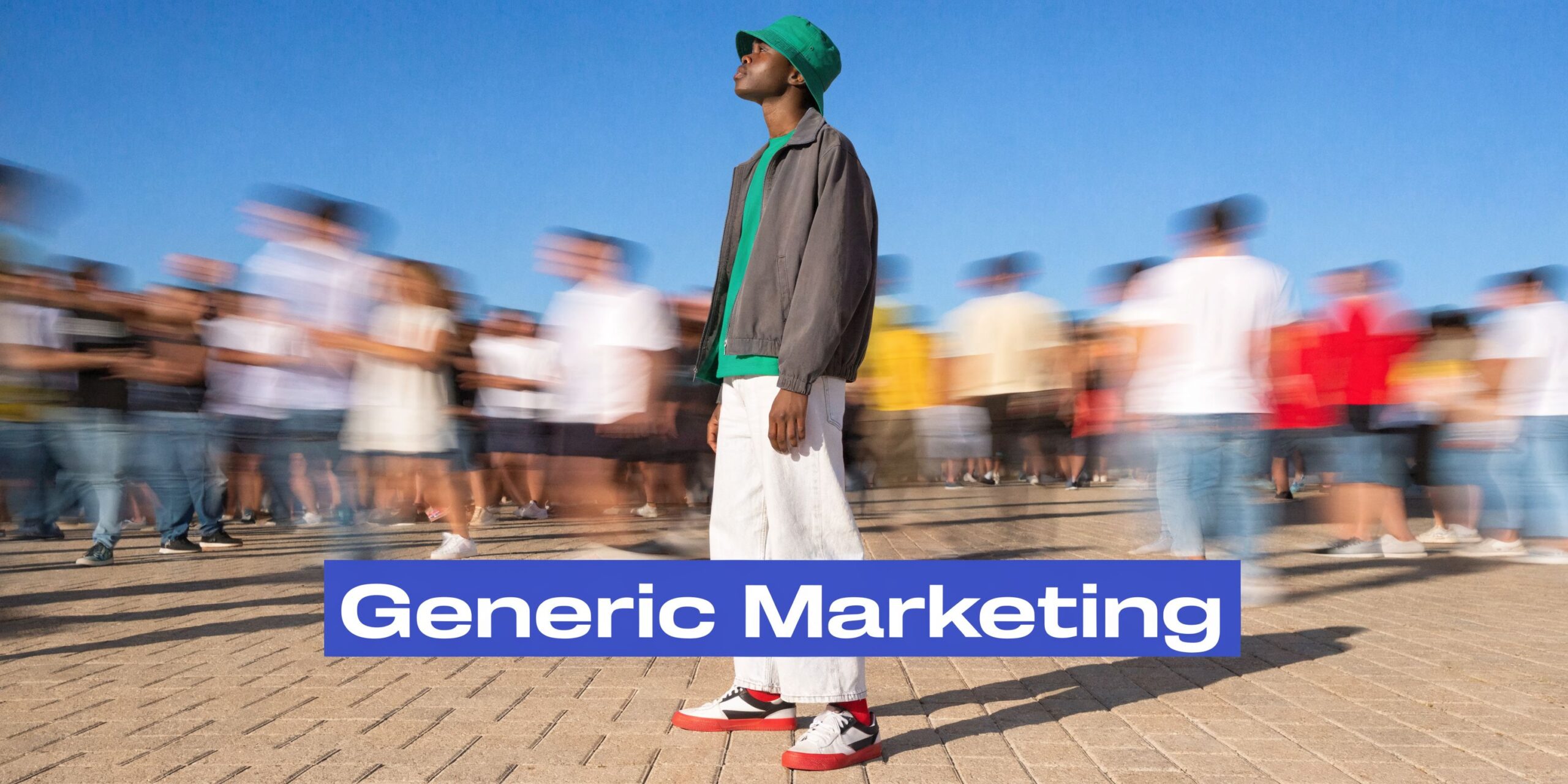 A young man stands still wearing a green bucket hat while a crowd of people blurs past him.