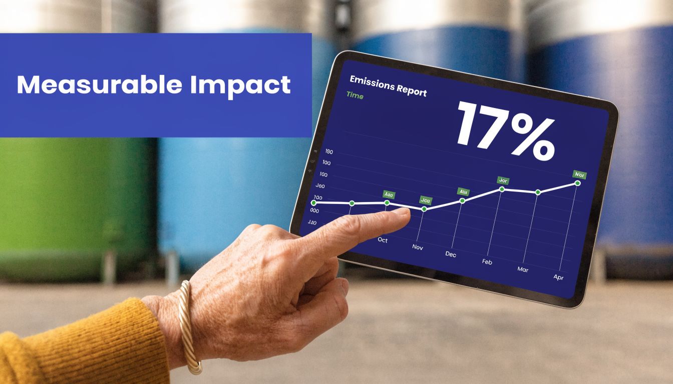 A person holding a tablet displaying a rising emissions report chart in an industrial setting.